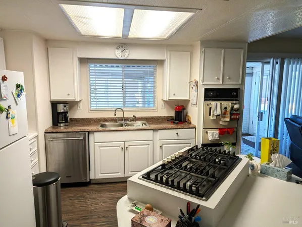 a kitchen with a stove a sink wooden floor and a window
