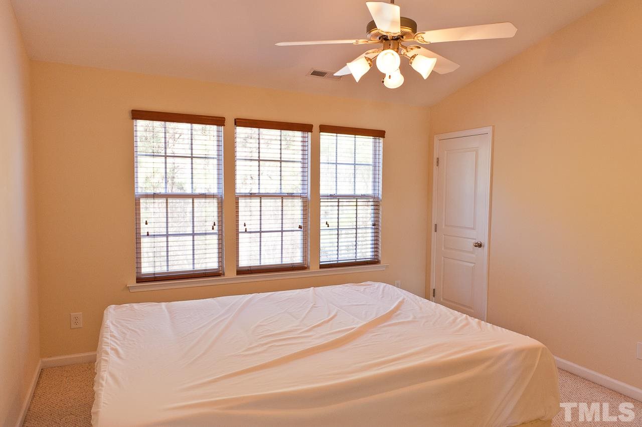7874 Spungold Street Raleigh, NC 27617 - Photo 14 of 18 a bedroom with a bed and a chandelier