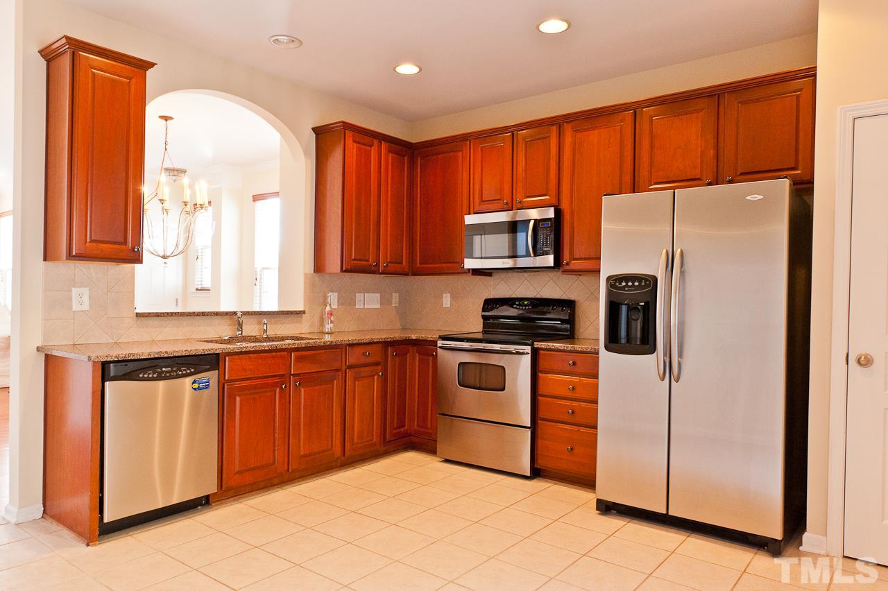 7874 Spungold Street Raleigh, NC 27617 - Photo 7 of 18 a kitchen with stainless steel appliances granite countertop a refrigerator and a stove top oven