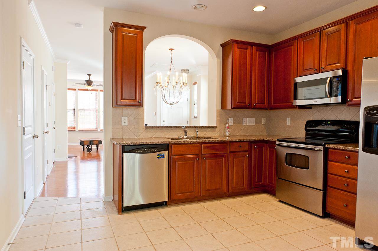 7874 Spungold Street Raleigh, NC 27617 - Photo 8 of 18 a kitchen with stainless steel appliances granite countertop a stove sink and cabinets
