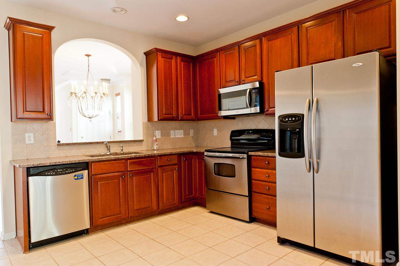 7874 Spungold Street Raleigh, NC 27617 - Photo 9 of 18 a kitchen with stainless steel appliances granite countertop a refrigerator and a stove top oven