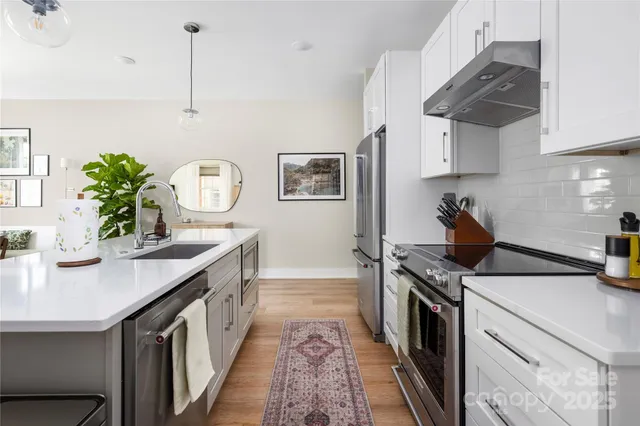 a kitchen with stainless steel appliances granite countertop a sink a stove and a wooden floors