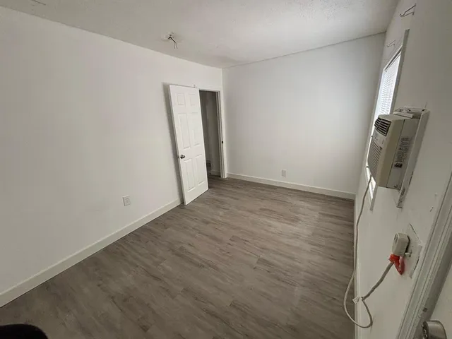 an empty room with wooden floor and mirror