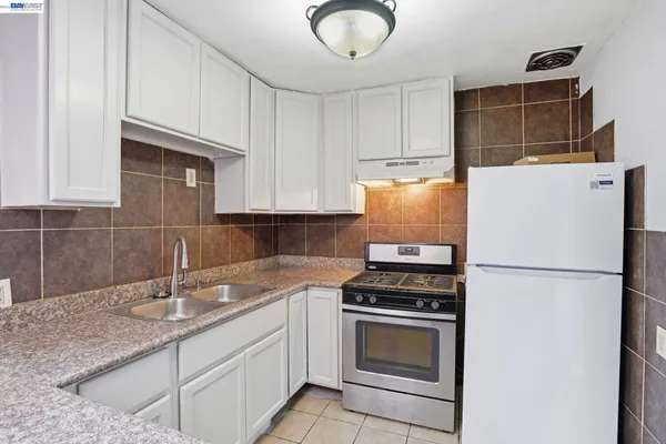 a kitchen with granite countertop a sink a stove and refrigerator