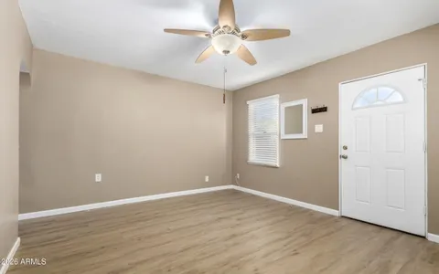 a view of an empty room with window and wooden floor