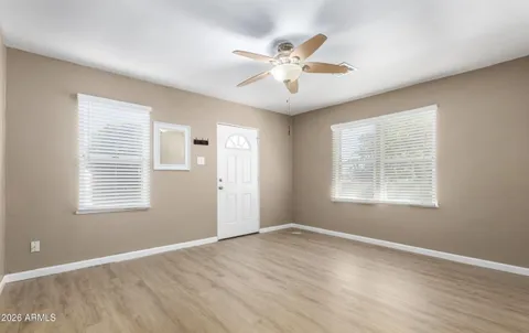a view of an empty room with wooden floor and a window
