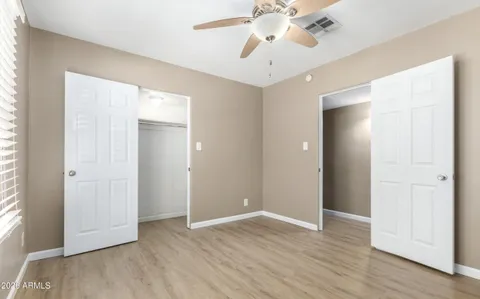 an empty room with wooden floor and ceiling fan