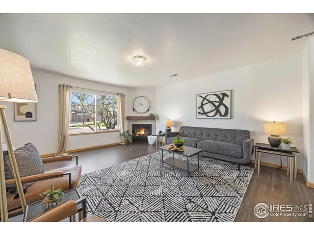 a living room with furniture a fireplace a rug and a window