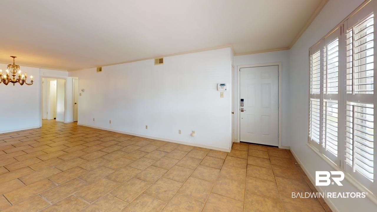 4009 Old Shell Road, Unit C13 Mobile, AL 36608 - Photo 7 of 32 Spare room featuring a chandelier, healthy amount of natural light, ornamental molding, and baseboards