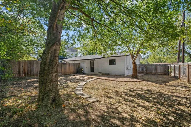 a backyard of a house with large trees and wooden fence