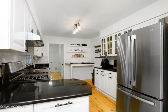 a kitchen with granite countertop a refrigerator stove and sink