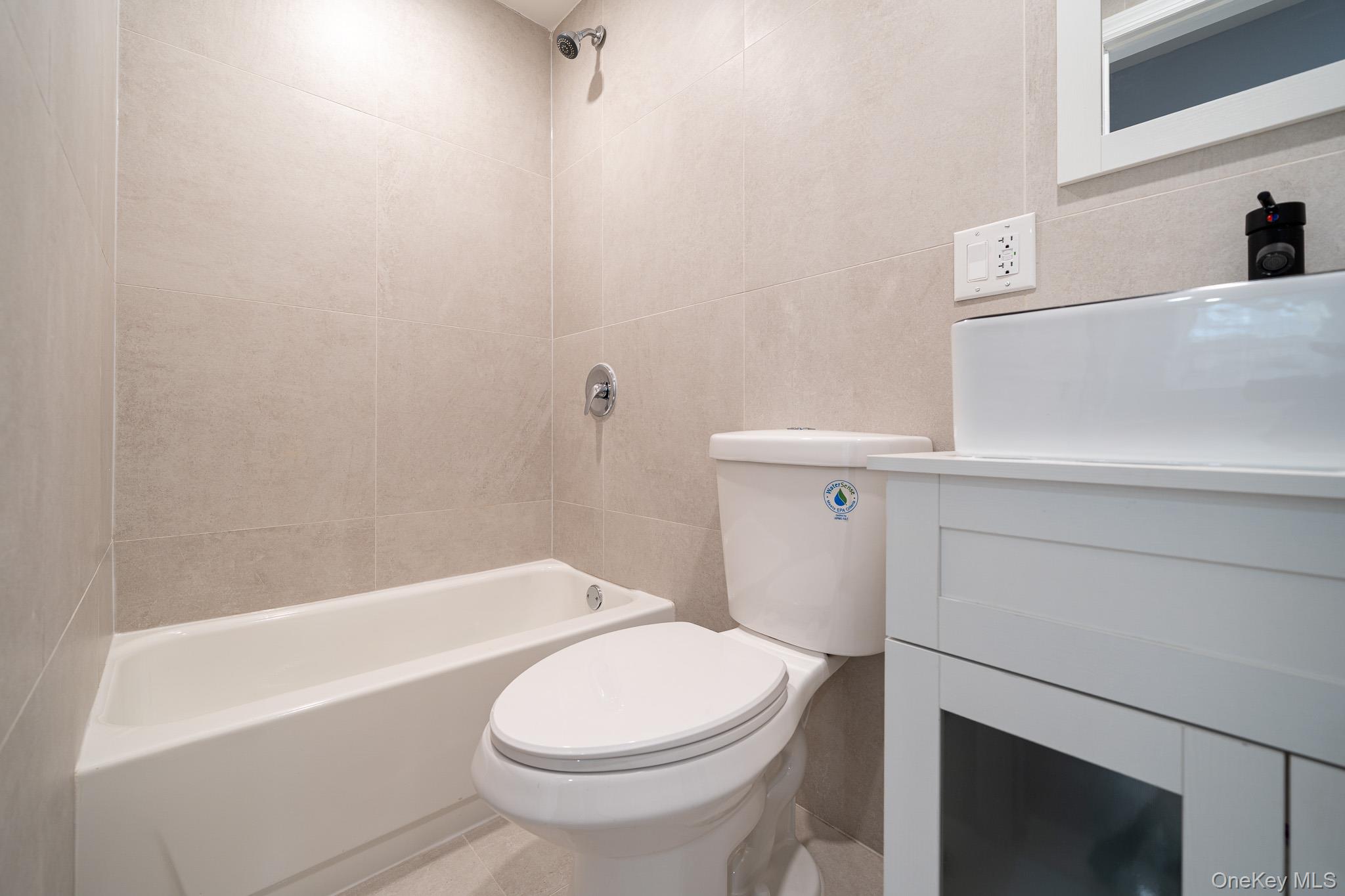 70-36 70th Street Queens, NY 11385 - Photo 7 of 29 Bathroom with vanity, shower / bathtub combination, and tile walls