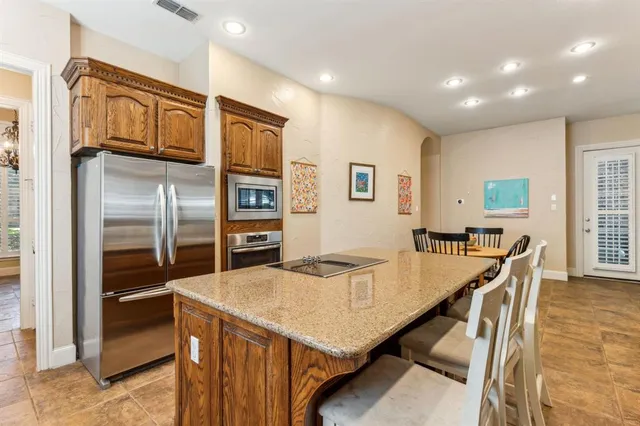 a kitchen with stainless steel appliances kitchen island granite countertop a refrigerator a stove a sink with island and chairs