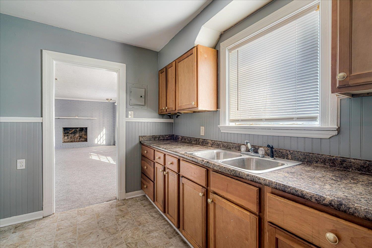 1114 Brownlee Road Memphis, TN 38116 - Photo 20 of 32 Kitchen with dark countertops, a fireplace, brown cabinetry, wainscoting, and wood walls