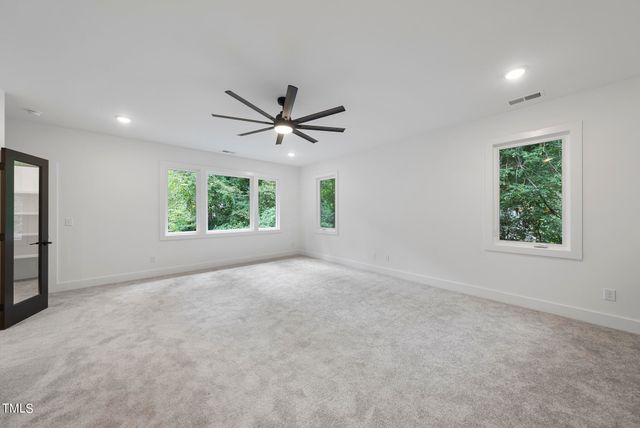 an empty room with windows and ceiling fan