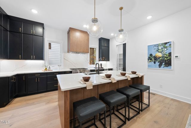 a large kitchen with a sink a counter space and chairs