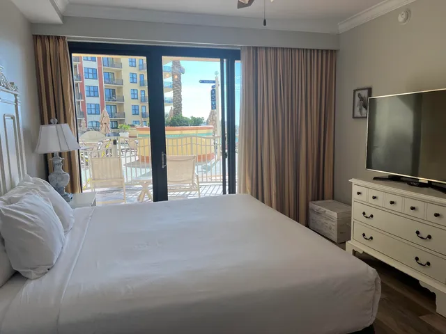 a bedroom with a large bed and a flat tv screen on dresser