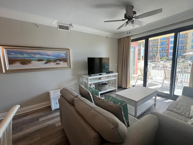 a living room with furniture a flat screen tv and a floor to ceiling window