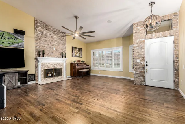 a view of a livingroom with a fireplace a chandelier and wooden floor