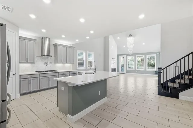 a kitchen with stainless steel appliances granite countertop a stove a sink dishwasher a refrigerator and white cabinets with wooden floor