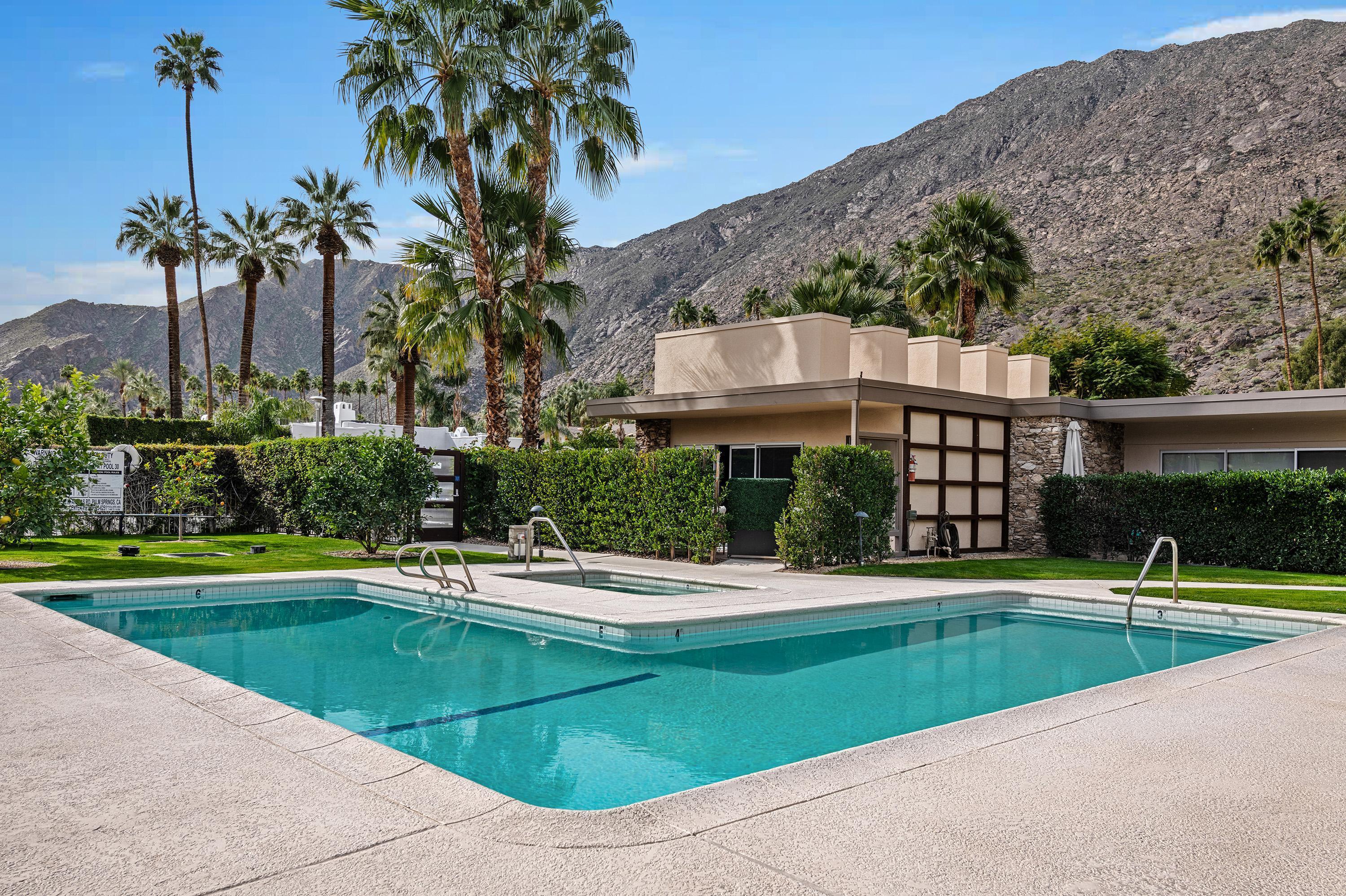 a view of swimming pool with a yard and palm trees