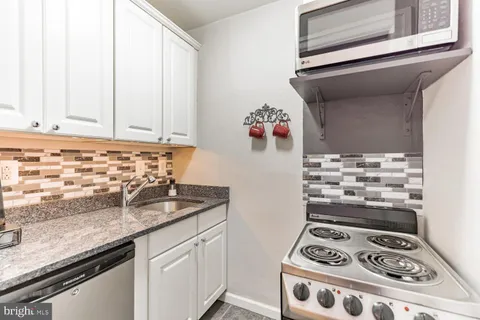a kitchen with granite countertop a sink stove and cabinets