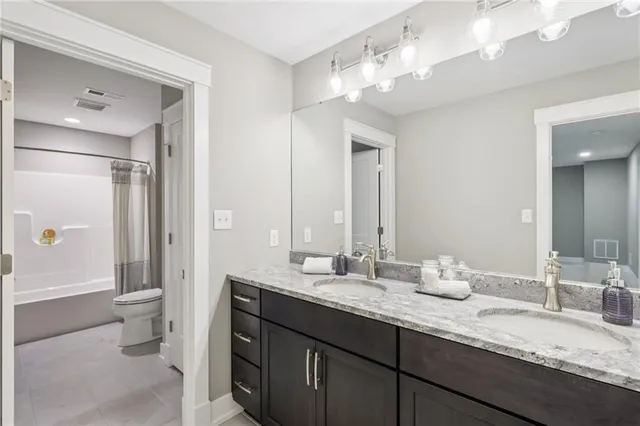 a bathroom with a granite countertop double vanity sink mirror and toilet