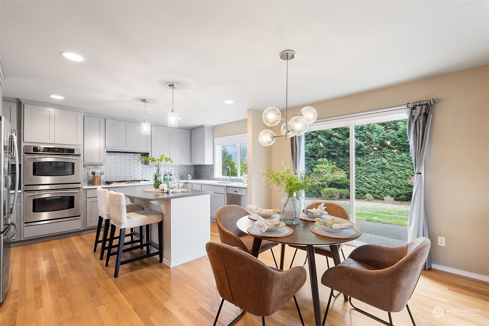 4411 240 Place Southeast Bothell, WA 98021 - Photo 13 of 36 a kitchen with stainless steel appliances a dining table chairs stove and white cabinets