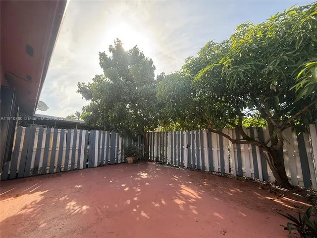 a view of backyard with wooden fence and trees