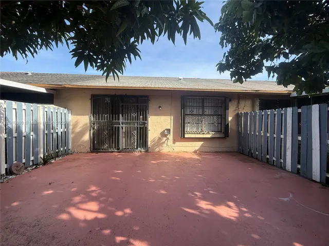 a view of a house with a yard and a large tree