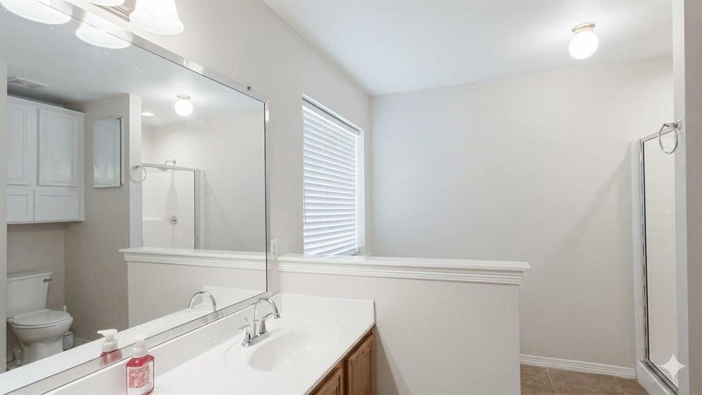 211 Vista Ridge Drive Venus, TX 76084 - Photo 13 of 24 Bathroom featuring a wood-finish vanity with an integrated white sink, an expansive wall-mounted mirror, a separate shower enclosure with a glass door, a window with horizontal blinds, and overhead lighting fixtures