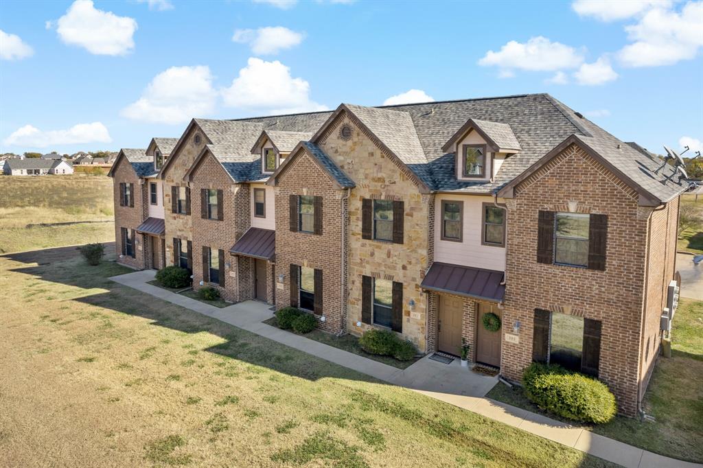 11118 Marion Road, Unit 105 Sanger, TX 76266 - Photo 1 of 29 Brick and stone exterior featuring dark wood shutters, individual metal awnings, and dormer windows