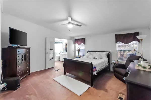 a spacious bedroom with a bed and a flat screen tv