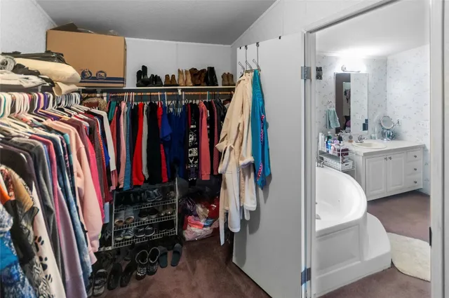 a walk in closet with clothes and shoes