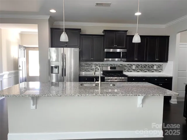 a kitchen with stainless steel appliances granite countertop a sink refrigerator and cabinets