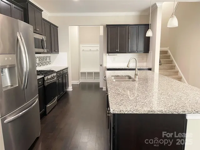 a kitchen with stainless steel appliances granite countertop a refrigerator a stove and a sink with wooden floor