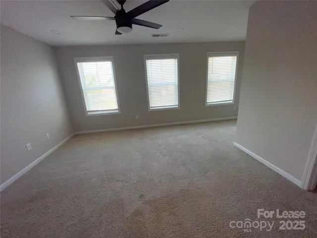 an empty room with windows and ceiling fan