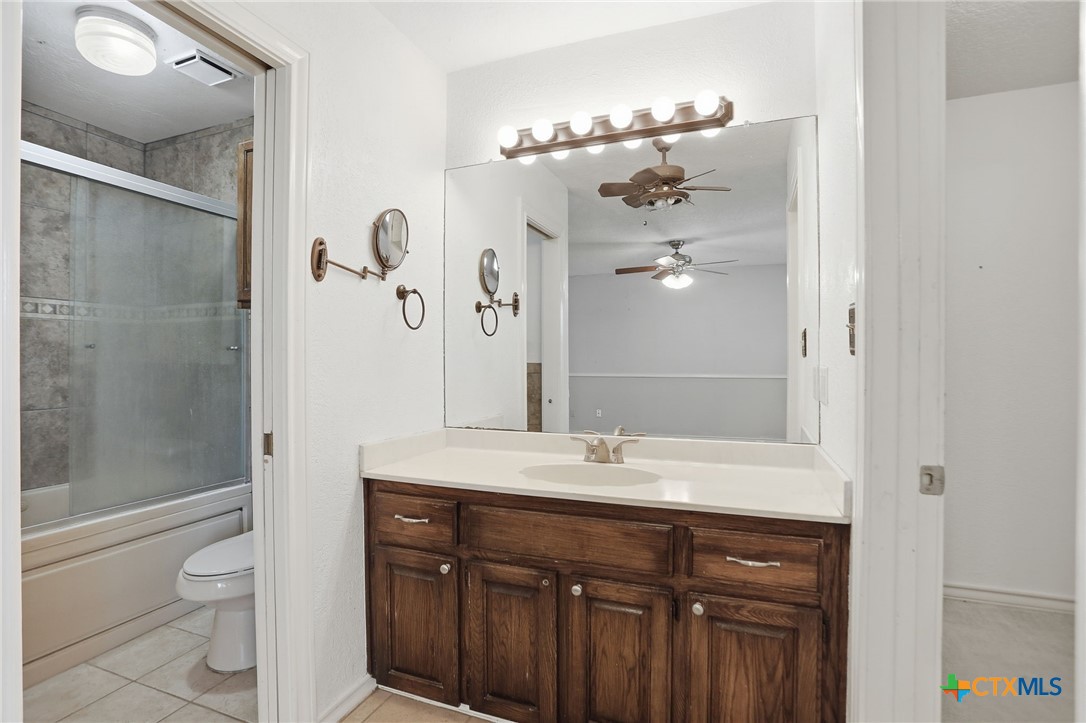 119 Primrose Drive Kyle, TX 78640 - Photo 19 of 30 a bathroom with a granite countertop sink a toilet a mirror and shower