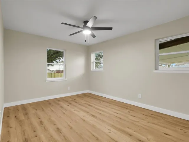 a view of empty room with wooden floor and fan