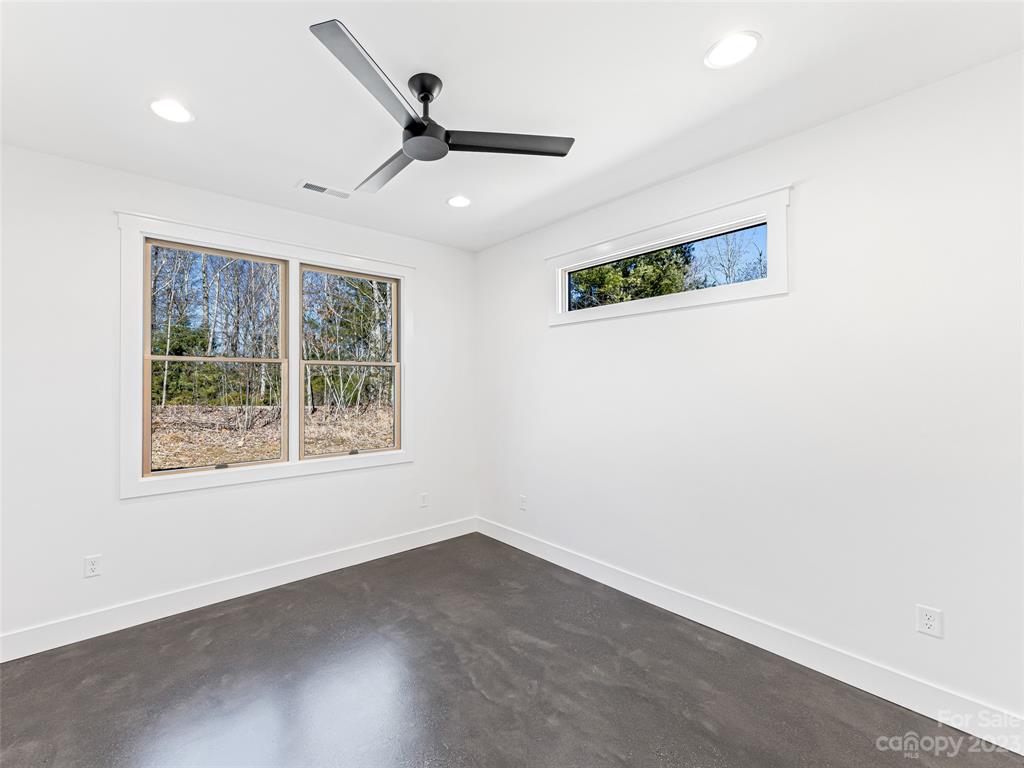 13 Small Crk Road Brevard, NC 28712 - Photo 39 of 48 an empty room with wooden floor ceiling fan and windows
