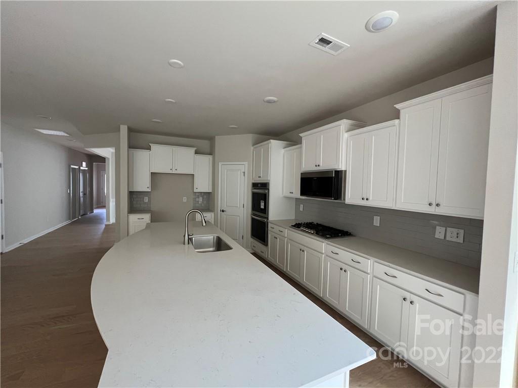 3137 Windhaven Lane, Unit 76 Tega Cay, SC 29708 - Photo 3 of 15 a kitchen with granite countertop a sink a counter top space stainless steel appliances and cabinets