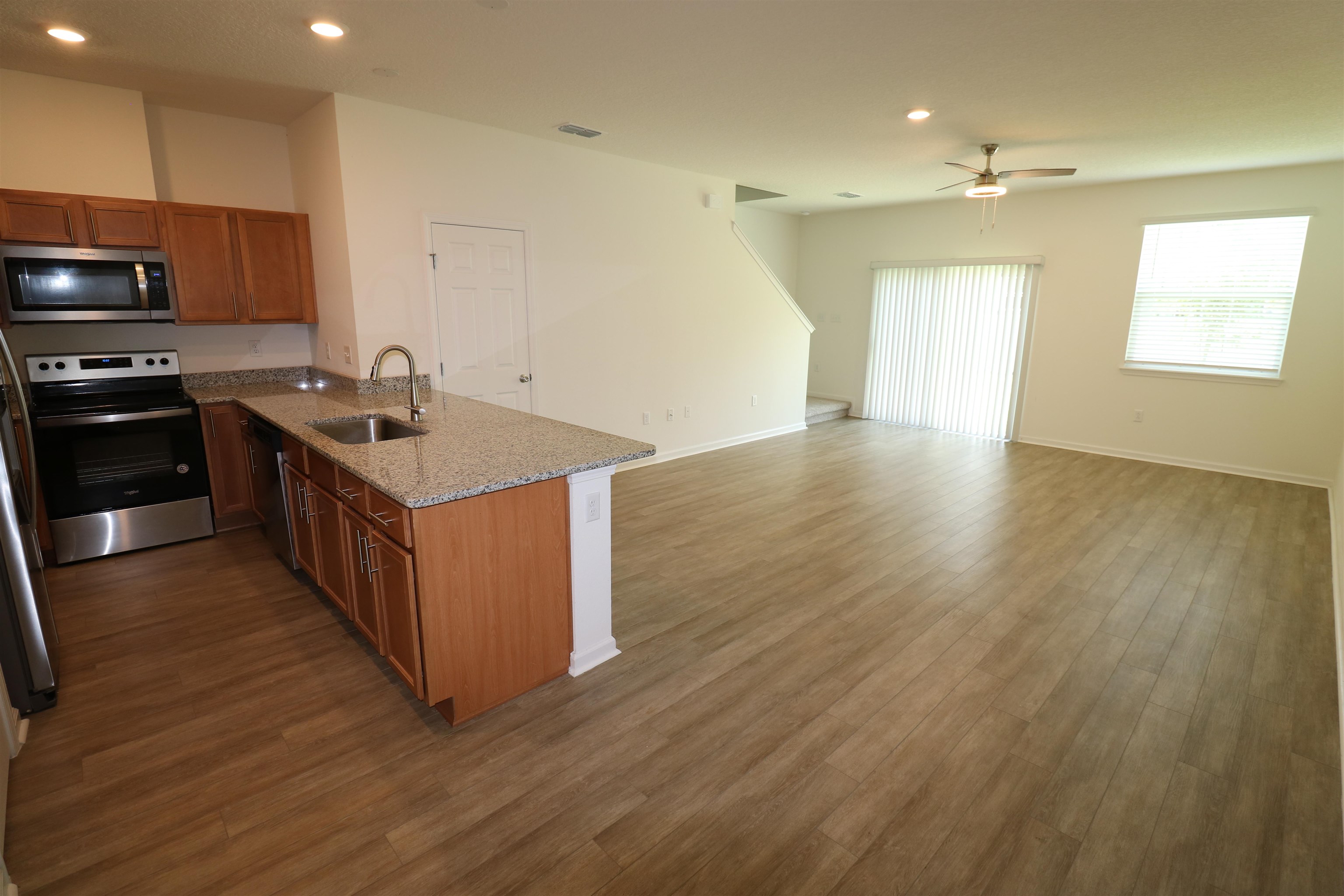 43 Mustard Hill St. Augustine, FL 32086 - Photo 2 of 25 Kitchen with a peninsula, wood finish cabinets, stainless steel appliances, light stone granite counters, and dark wood-style flooring