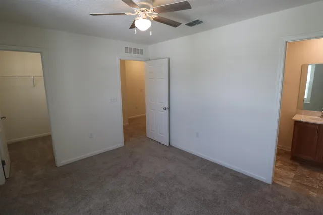 an empty room with closet and a chandelier fan