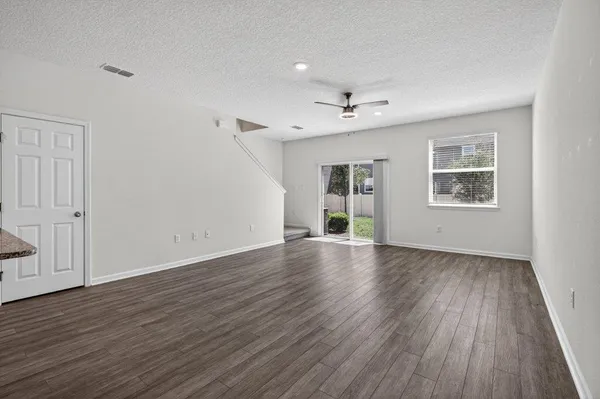 an empty room with ceiling fan and windows