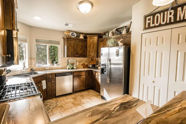 a kitchen with stainless steel appliances granite countertop a refrigerator a stove and a sink