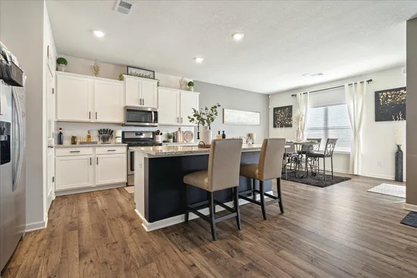 a kitchen with a dining table chairs refrigerator and cabinets
