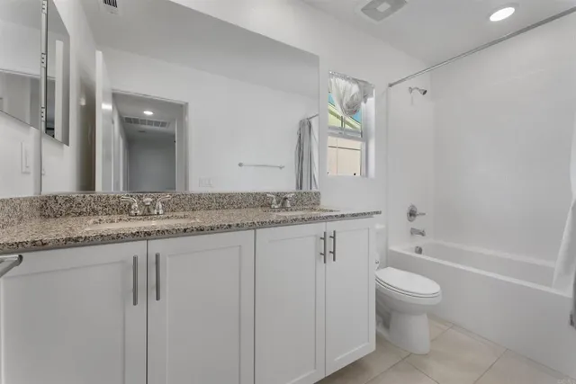a bathroom with a granite countertop sink a toilet and bathtub