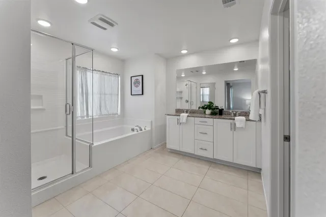 a large white bathroom with a large mirror vanity and bathtub