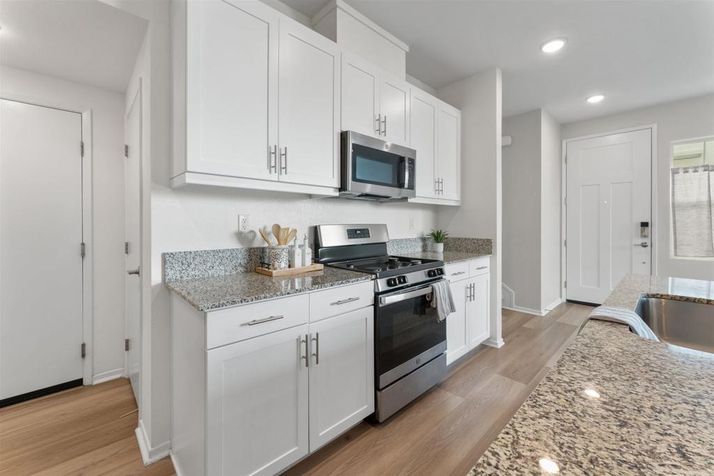 212 Perennial Place Fallbrook, CA 92028 - Photo 5 of 39 a kitchen with stainless steel appliances granite countertop white cabinets a sink a stove a refrigerator and microwave with wooden floor