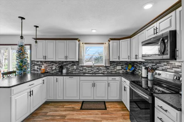 a kitchen with stainless steel appliances granite countertop a stove a sink and a microwave